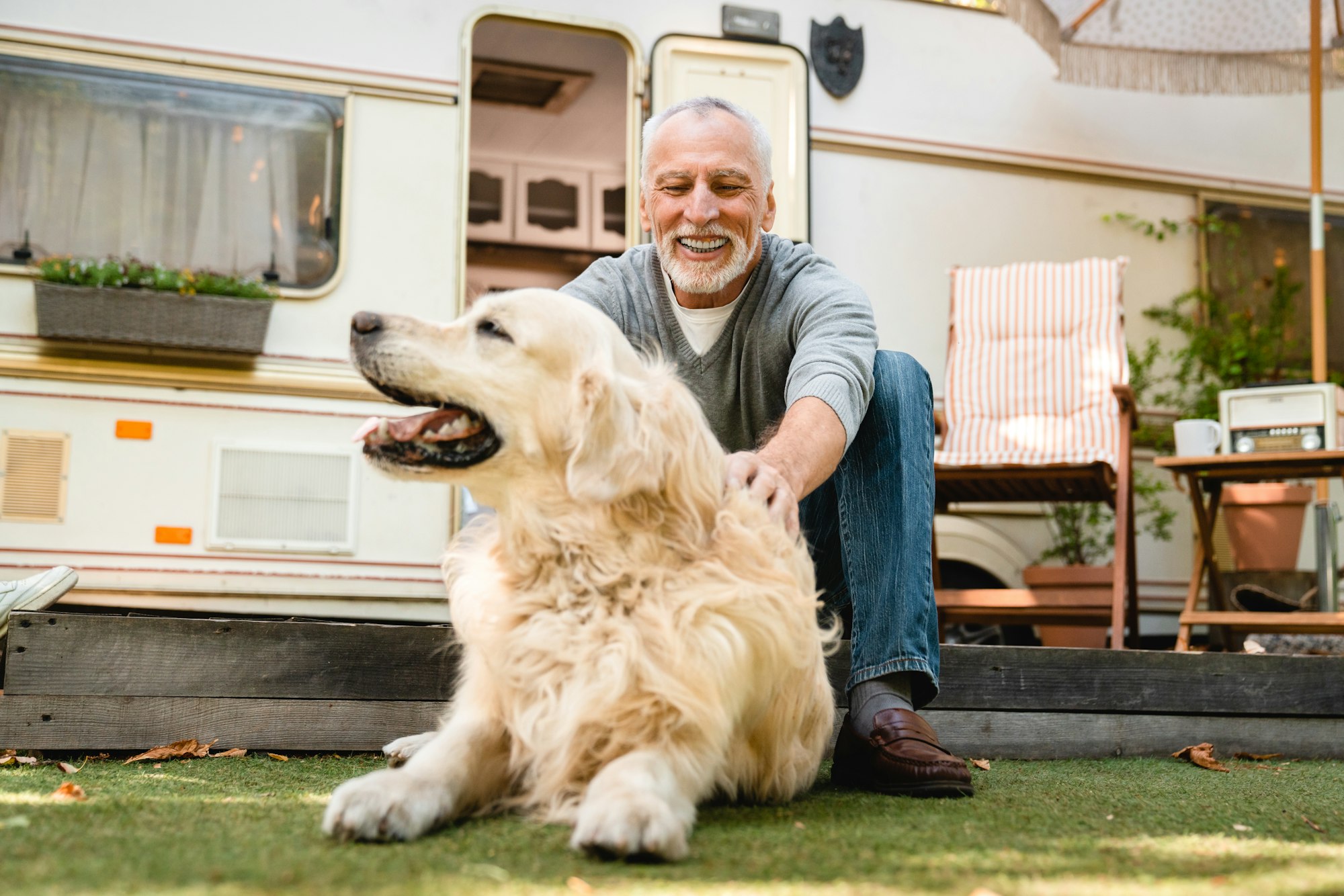 senior man with his aging golden retriever dog in front of camper